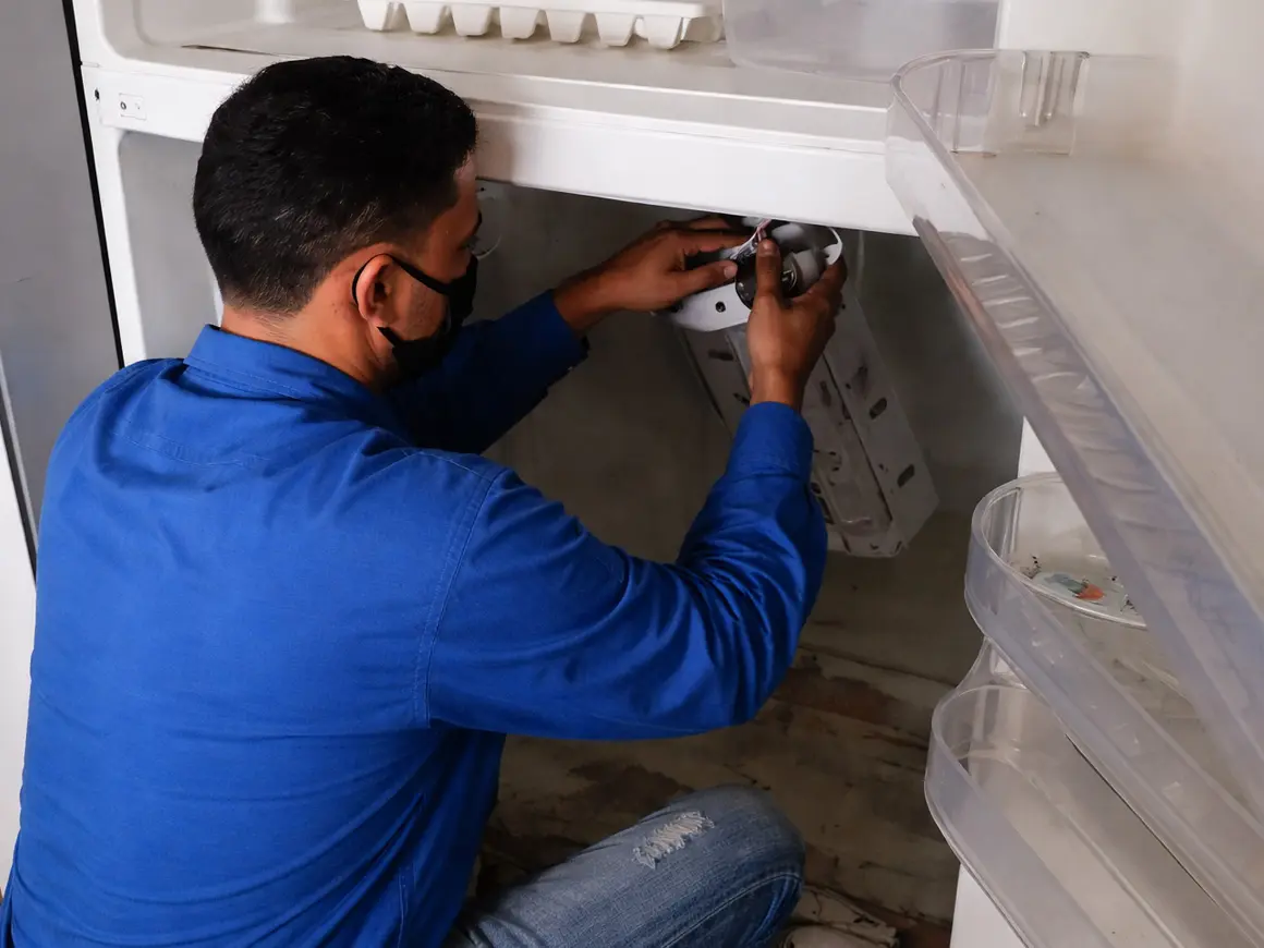 Técnico de RepararYa inspeccionando el interior de una nevera en domicilio en Barranquilla